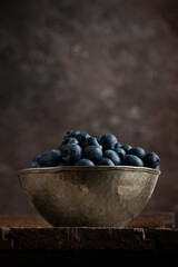 Bowl of fresh blueberries on rustic wooden table with copy space.
