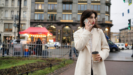 Business woman with coffee in hands speaks on the phone