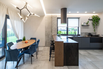 Contemporary interior of kitchen in luxury private house. Table and chairs. Wooden counter. Stylish home decor.