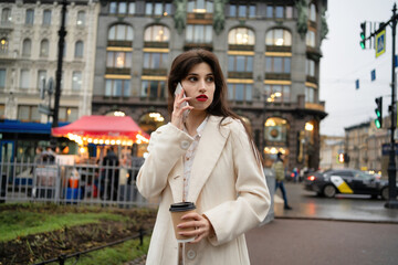 Business woman with coffee in hands speaks on the phone