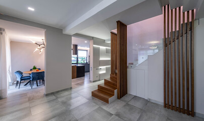 Contemporary interior of luxury apartment. Wooden staircase. Modern kitchen. Table and blue chairs.