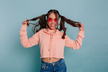 Funny attractive woman with collected hair wearing pink pullover playing with her hair wearing...