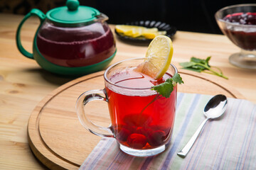 Berry tea in a cup and a teapot on a table on a round wooden stand top view.