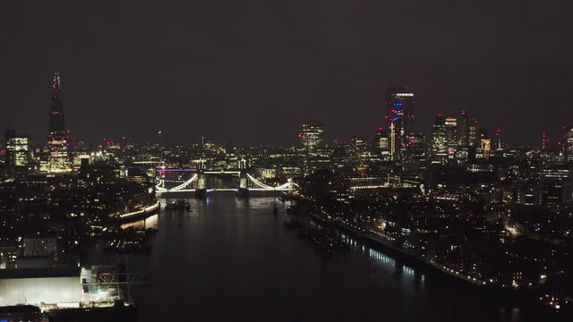 dolly forward drone shot of London city centre skyscrapers tower bridge at night
