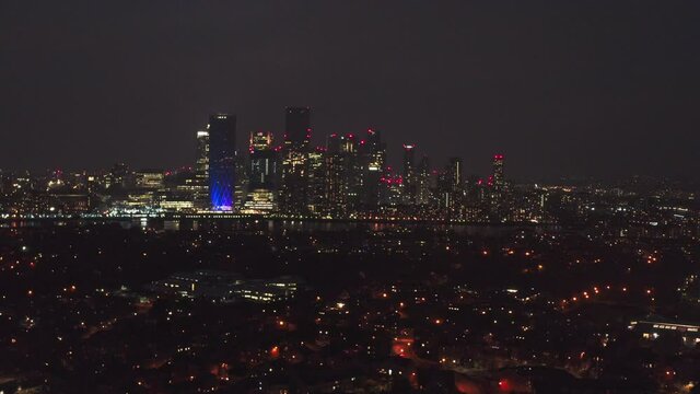 Long slider drone shot of Canary wharf skyscrapers at night over Rotherhithe