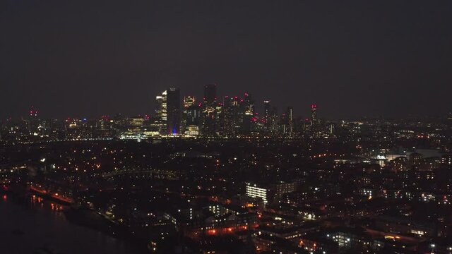 Dolly forward drone shot towards Canary wharf skyscrapers at night