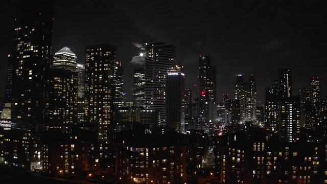 dolly forward aerial shot of Canary Wharf buildings at night full moon