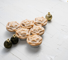 Closeup of toy balls and mince pies with a star-shaped ornament, stacked like a small Christmas tree © Max Rushent/Wirestock