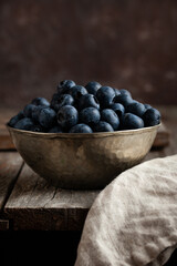 Bowl of fresh blueberries on rustic wooden table.