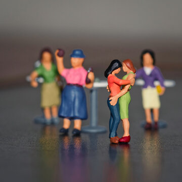 Lesbian miniatures dancing with other female miniature figurs on the background