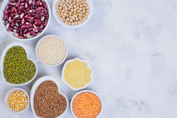 A variety of cereals and legumes on a light background. Lentils, red beans, quinoa, chickpeas, Munch, crushed peas, millet, buckwheat. Gluten-free products. The view from the top.