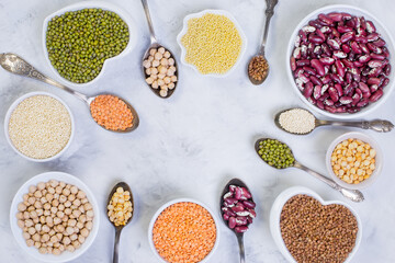A variety of cereals and legumes on a light background. Lentils, red beans, quinoa, chickpeas, Munch, crushed peas, millet, buckwheat. Gluten-free products. The view from the top.