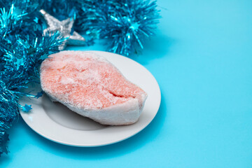 frozen salmon on white plate on blue background