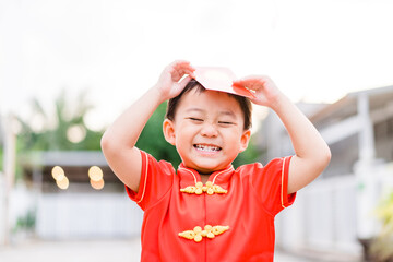 Happy chinese new year kid boy.Asian toddler boy wearing chinese traditional cheongsam qipao shirt showing red envelope at home.Happy chinese new year concept.Holidays in asian people.Stay home save.