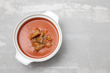 tomato soup in white bowl on ceramic background