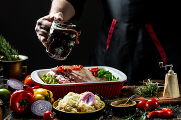 Professional cook prepares Roasted pork. Bavarian pork knuckle with sauerkraut and beer. German cuisine, freeze motion