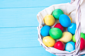 basket with colorful Easter eggs on a blue wooden background, selective focus, tinted image