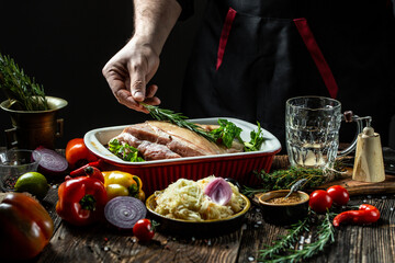 Chef hands cooking pork knuckle and adding fresh rosemary on black vertical image, place for text