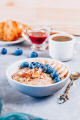 Healthy breakfast - oatmeal, croissant and coffee on a table