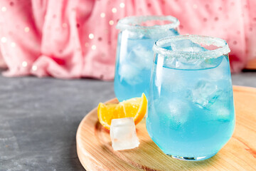  Cocktail with ice and blue curacao on a delicate pink background