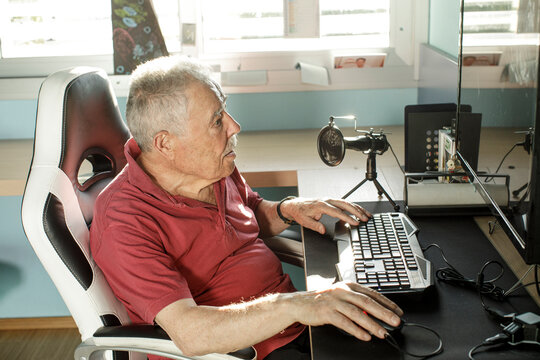 Anziano signore con un paolo &egrave; seduto di fronte al computer mentre di una camerata mentre utilizza il mouse 