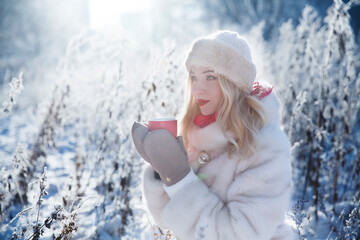beautiful girl drinks hot tea or chocolate in the cold on a winter walk