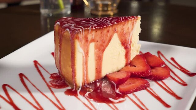 Decadent strawberry cheesecake, fresh strawberries and drizzle decorate slice, slider slow motion 4K