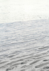 many footprints from shoes on white snow vertical frame on the background of water in the river