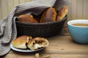 baked pies with apple and hot tea on the wooden table