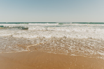 Front view of the beach with brown sand and the blue sea with waves in the coast of Spain in Tarragona
