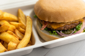 Cheeseburger with freshly made fries ordered for take away or to be delivered home