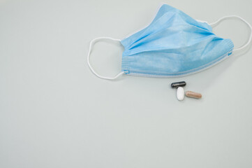 Medical mask with capsules on gray background - the concept of new normal
