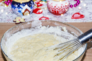 Kneading cookie dough on the background of Christmas decorations, whisk close-up. Selective focus