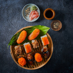 The flat lay of the Japanese food assortment - sushi, nigiri, tempura, maki, sashimi on dark background with copy space. Traditional Japanese cuisine. Asian restaurant concept menu.