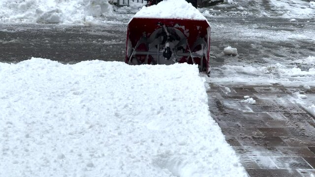 Person removing snow from drive way with snow removal machine