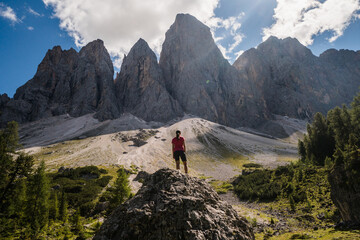 Fototapeta na wymiar Young hiker with the back at the camera looking towards the cliffs in the Dolomites, Italy.