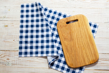 Top view of checkered napkin tablecloth on white wooden table. Empty cutting square board.