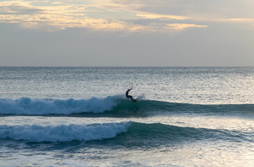 Fototapeta premium Surfer boy doing a trick on the wave while riding on his board in the perfect surfing spot at El Palmar