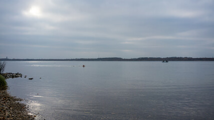 Man swims in cold water on a moody day in autumn 