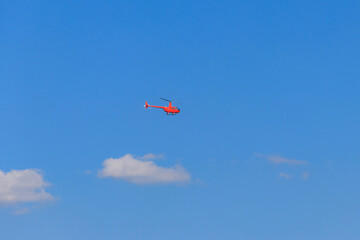 Flying orange helicopter in blue sky