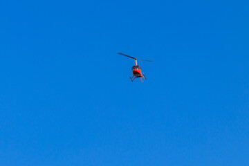 Fototapeta na wymiar Flying orange helicopter in blue sky