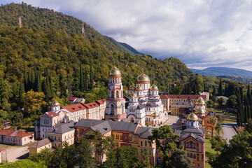 Fototapeta na wymiar Aerial view of ancient monastery New Athos in sunny summer day, green forest with mountains and church, religious place