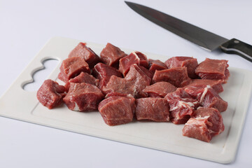 Sliced raw beef on a plastic board on white background. Horizontal format