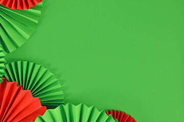 Red and Green paper craft rosettes in traditional Christmas colors on side of  green background...