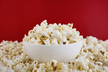 Popcorn in a white bowl on a red background. Selective focus. Corn snacks. close up.