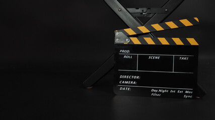 Fototapeta na wymiar Director chair and Clapper board or Clapperboard or movie slate use in video production or film and cinema industry. It's put on black blackground.