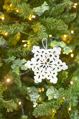 snowflake crocheted on the background of a Christmas tree defocused sparkling lights