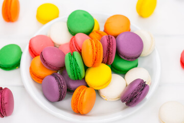 Colorful French macaroons on the white wooden background close up