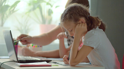 Cute children use laptop for education, online study, home studying, Boy and Girl have homework at distance learning. Lifestyle concept for home schooling. Father helps daughter and son.