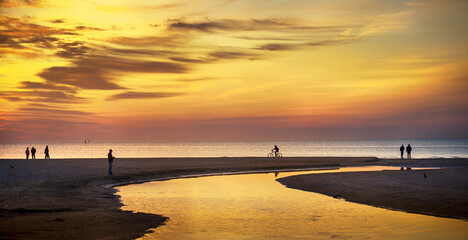 Silhouettes of people and man on bike enjoying a walk by the Black sea coast in Anapa, Russia.